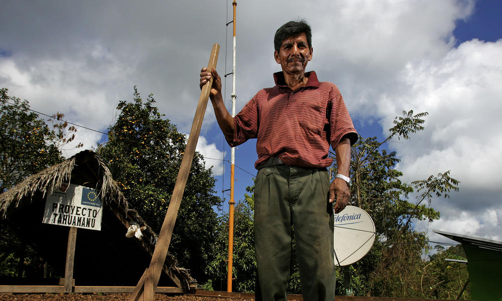 A sustainable Brazil nut farmer standing amongst his drying brazil nuts.