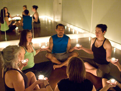 A yoga group holding candles