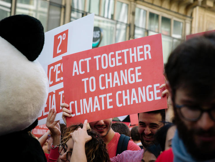Sign reading "act together to change climate change" from the 2018 Paris Climate March