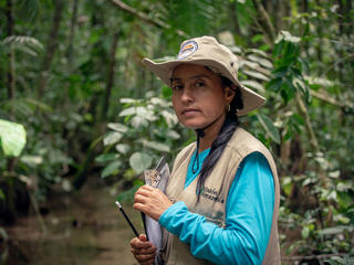 Portrait of Marisela Silva Parra standing in the forest with a clipboard
