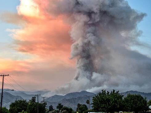 A tower of smoke rises from a wildfire. 