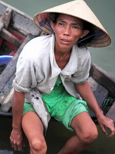 Vietnamese fisherman collects a shellfish in the Thu Bon River at Hoi An, Vietnam.