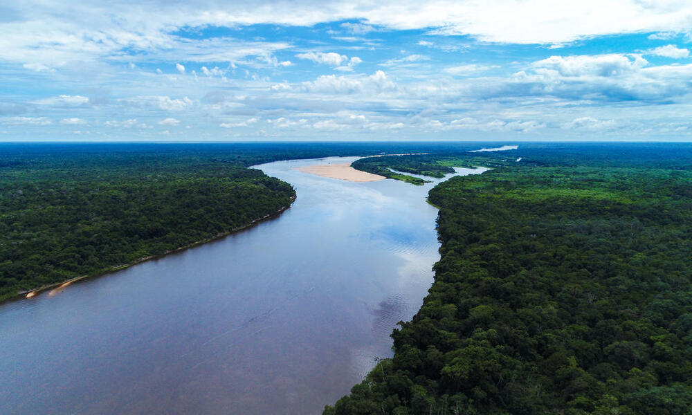 Aerial view of a free-flowing blue river snaking through the green Bolivian Amazon