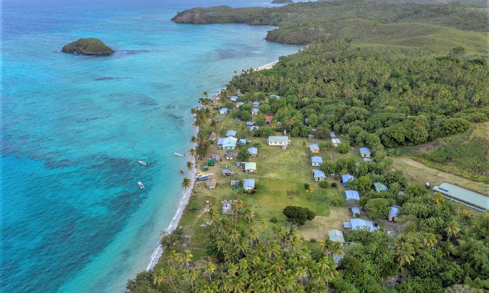 Aerial view of a fishing community along the coast nestled up against clear blue waters
