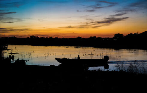 Sunset along river with canoe silhouette