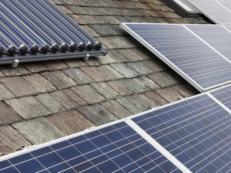 Solar voltaic electricity generating panels and solar hot water panels on a house roof in Ambleside, Cumbria, UK.
