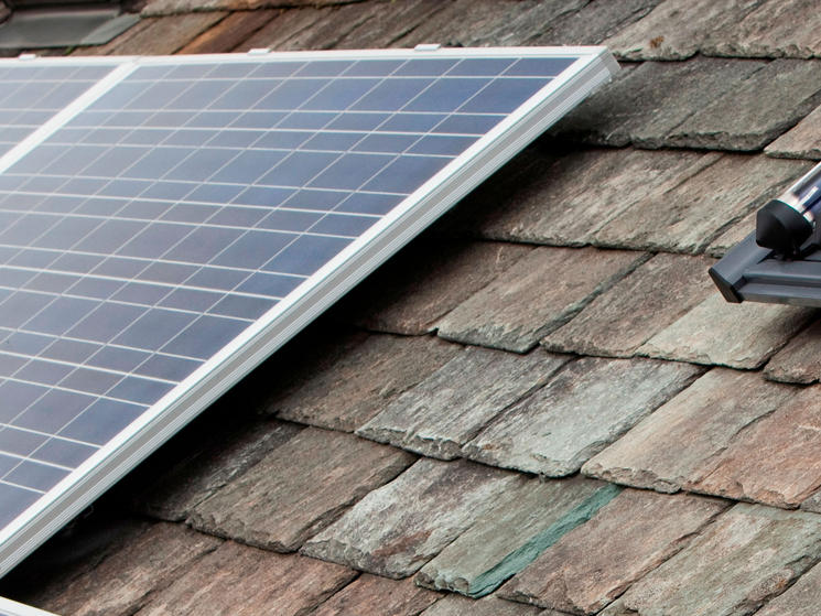 Solar voltaic electricity generating panels and solar hot water panels on a house roof in Ambleside, Cumbria, UK.