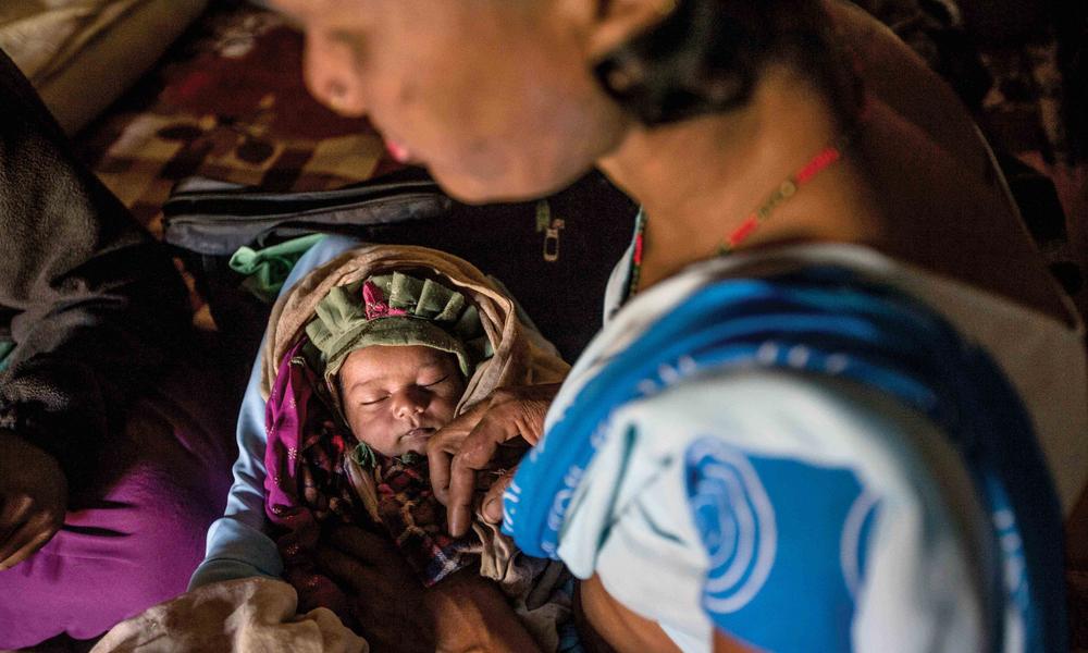 Wearing the blue sari that conveys her training, Devi cradles a baby she delivered a week earlier, checking the infant’s temperature, heartbeat and other vital signs.