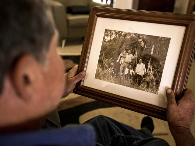 Gerry Deguara looking at a family portrait, His father came over from Malta when he was 14 years old and began cane havesting by hand. Mackay, Queensland, Australia.